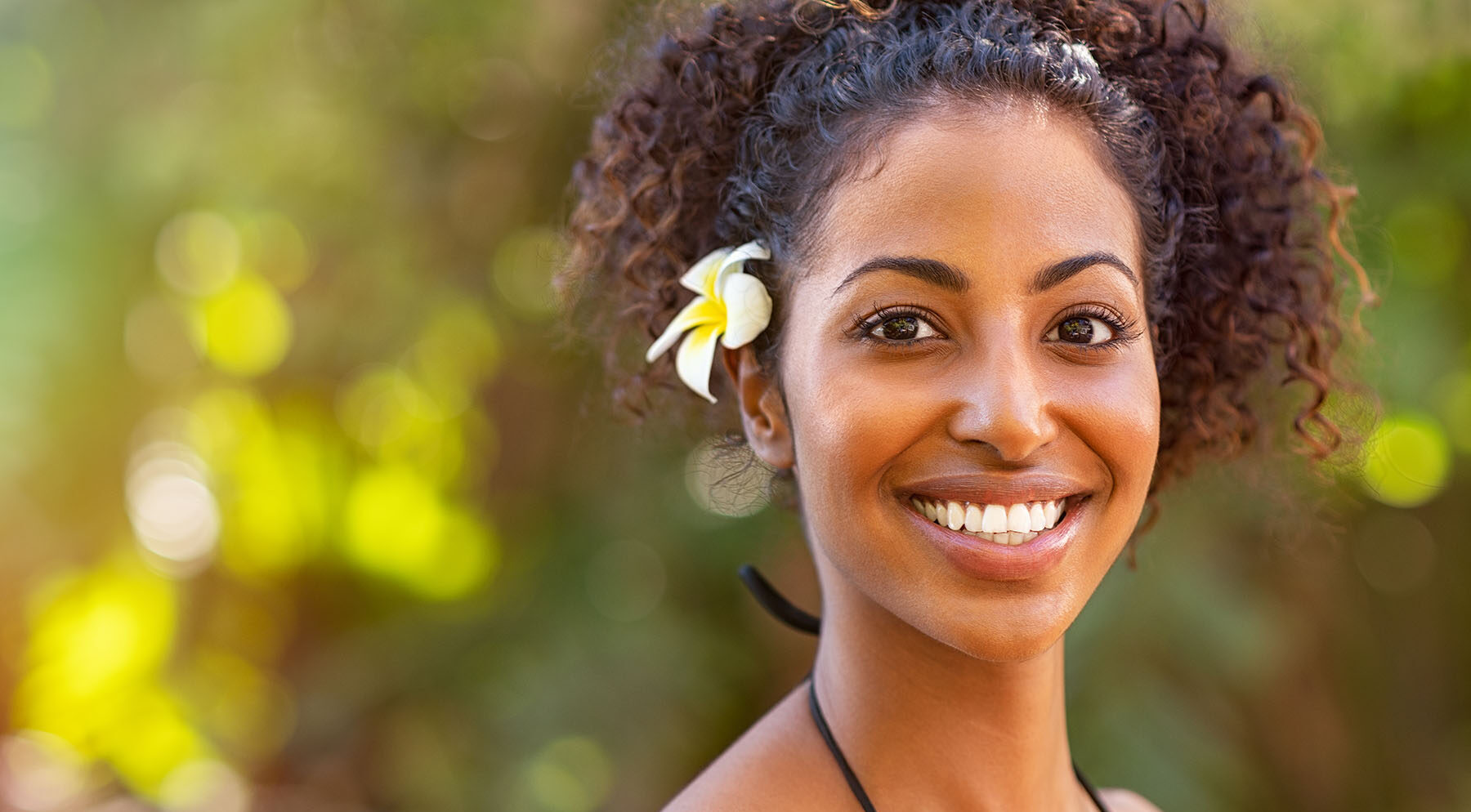 Close-up of pretty Black woman with great hair, smiling in the sun.