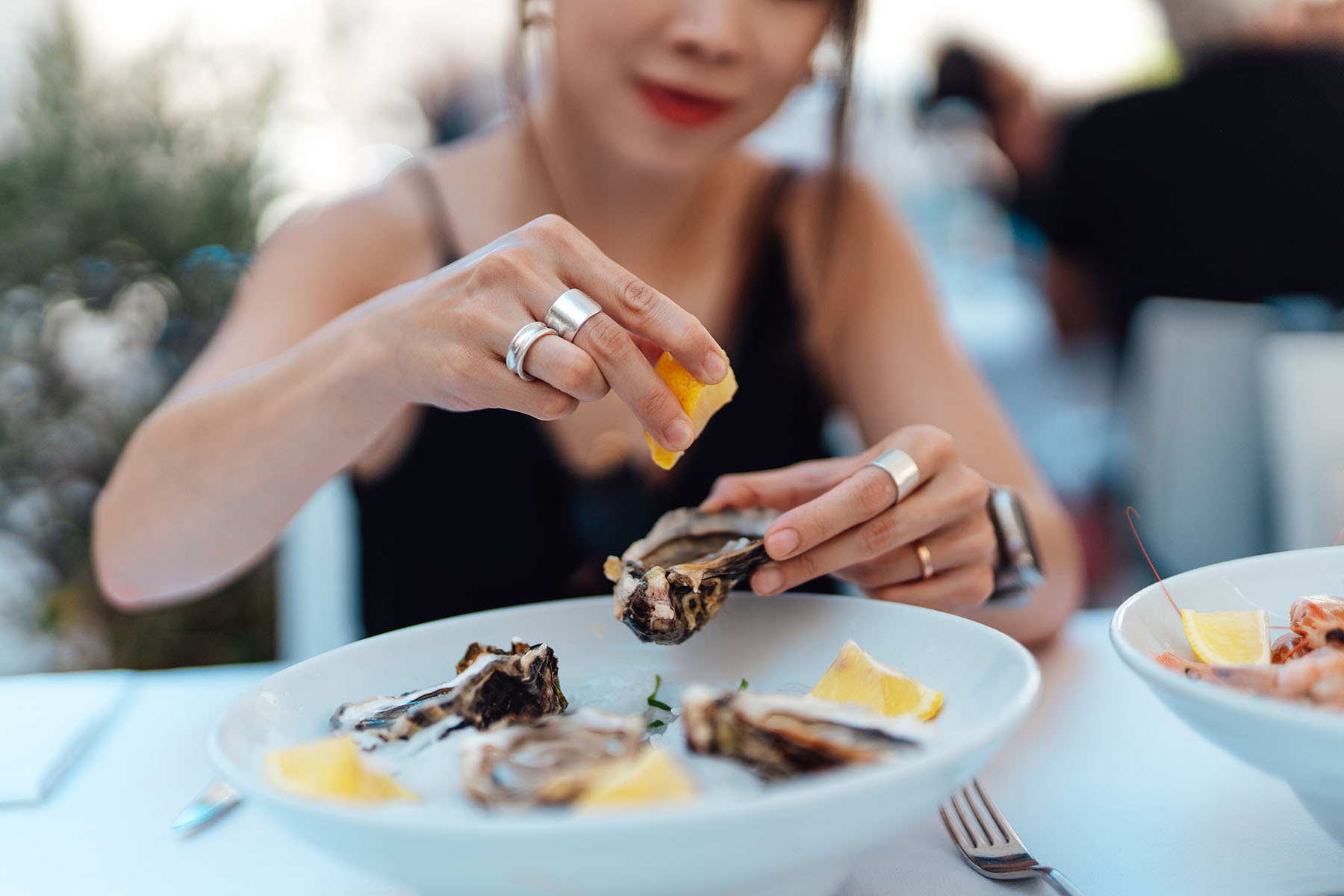 Woman sprinkling lemon on fresh raw oysters.