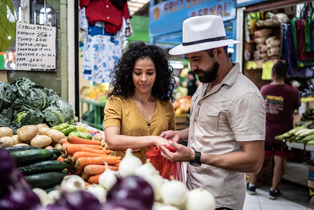 Young Hispanic couple shops for vegetables at a fresh market.