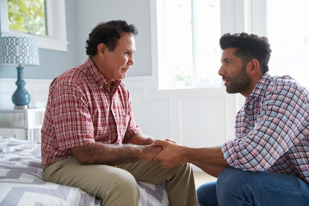 Adult Hispanic son comforts his aging dad.