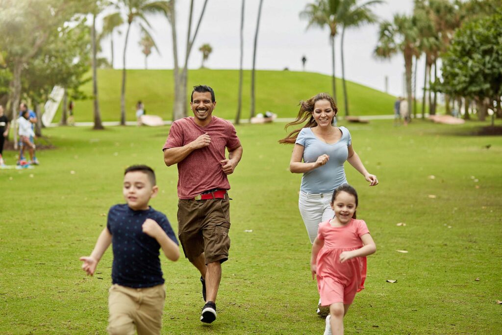 Hispanic family plays at a local Miami park, having fun and staying fit.