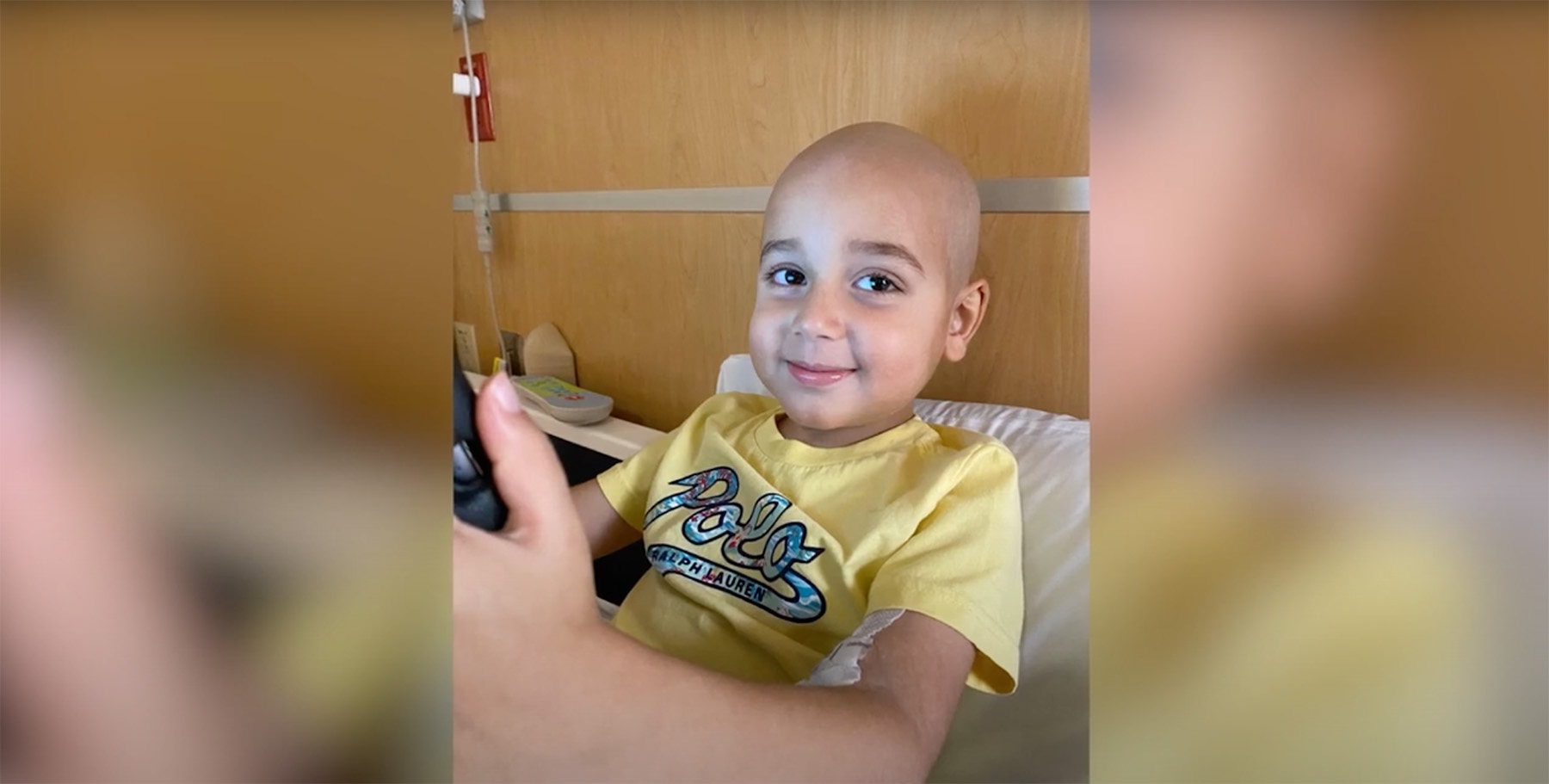 An adorable pediatric leukemia patient smiles at the camera.