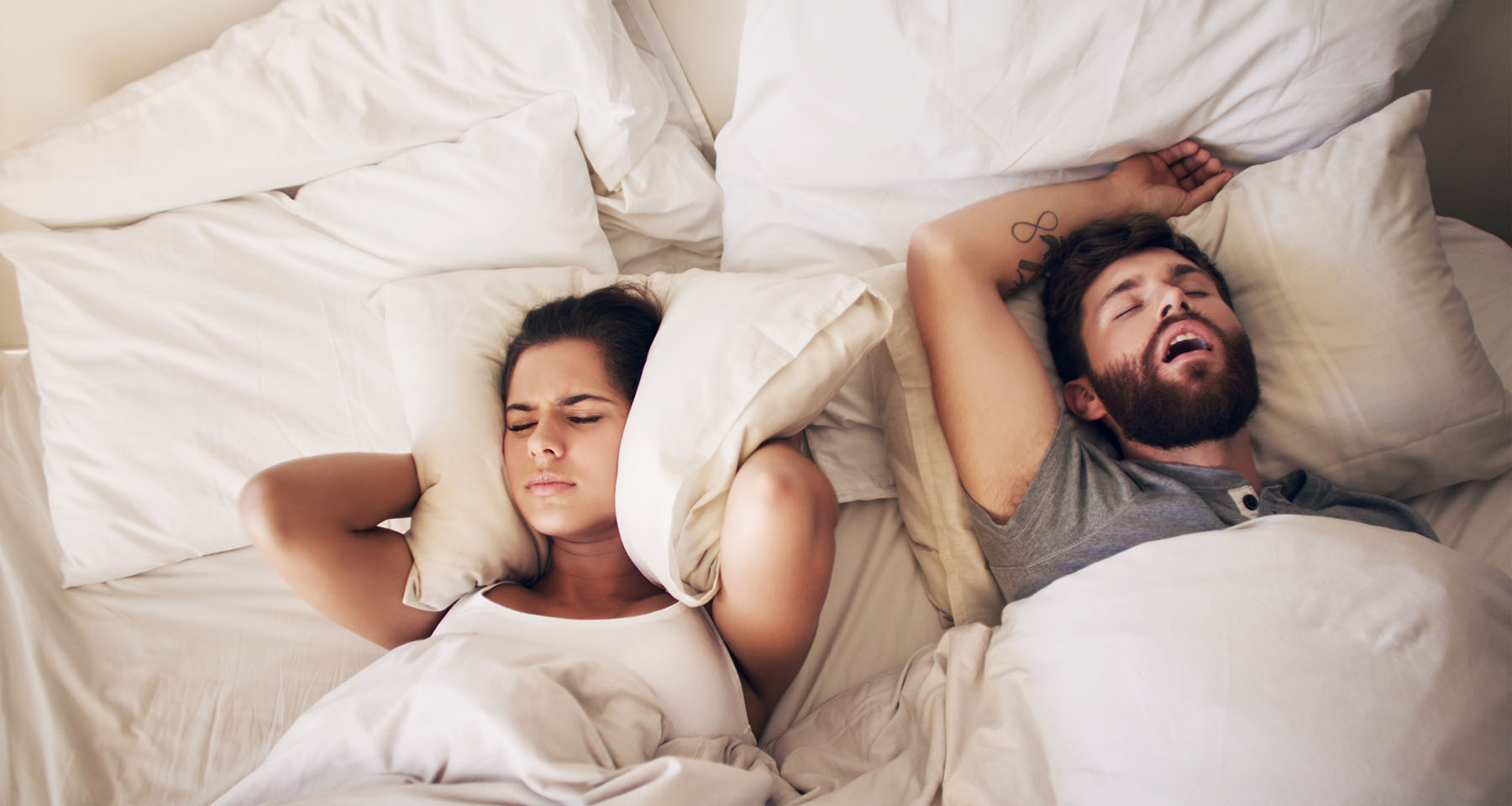 Couple in bed. Woman can't sleep because man is snoring from sleep apnea.