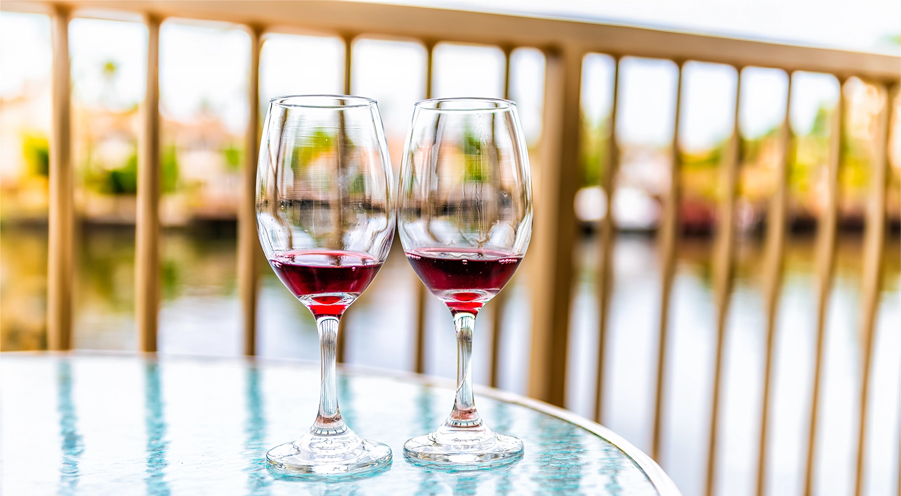 Two glasses of red wine sit on a patio table in Miami.