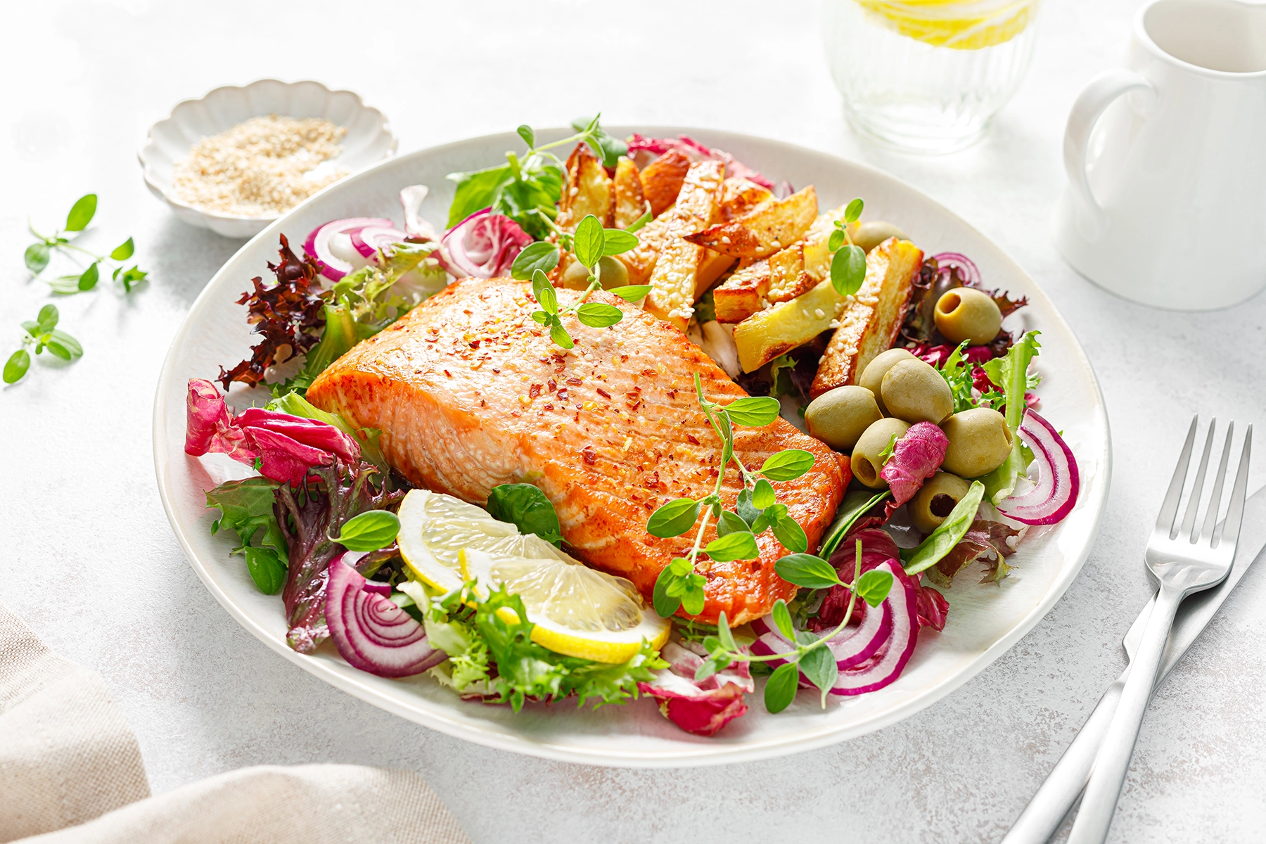 A bowl of salmon and salad, including olives, representing the Mediterranean diet.