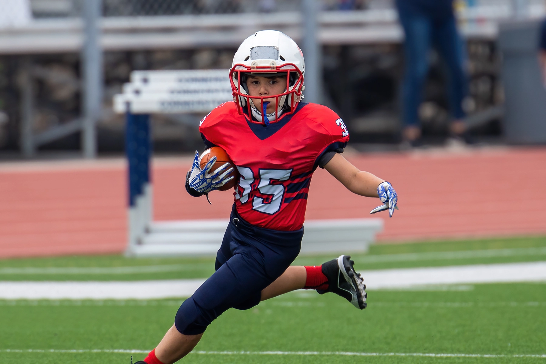 Young kid playing wide receiver for a tackle football team.