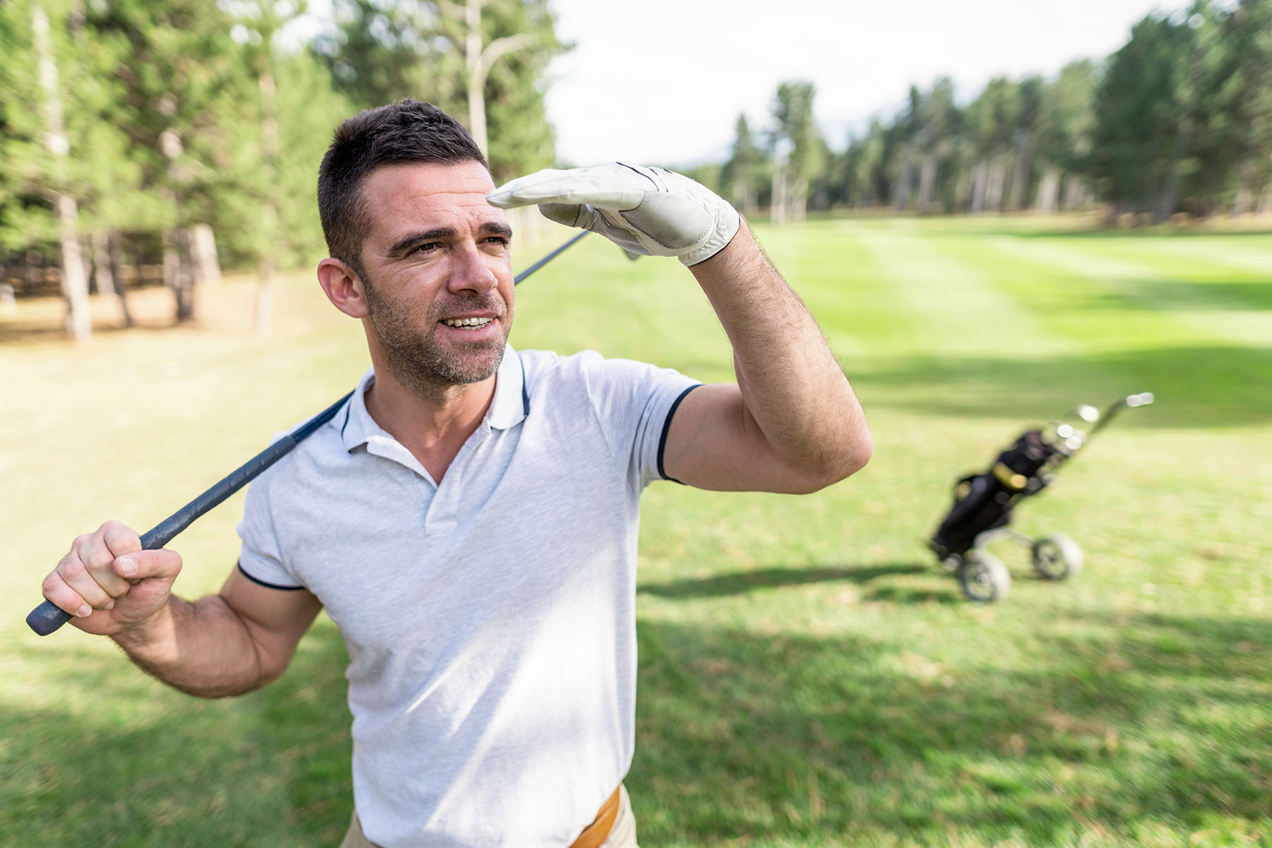 Man looks to the distance judging how far he hit a golf ball.