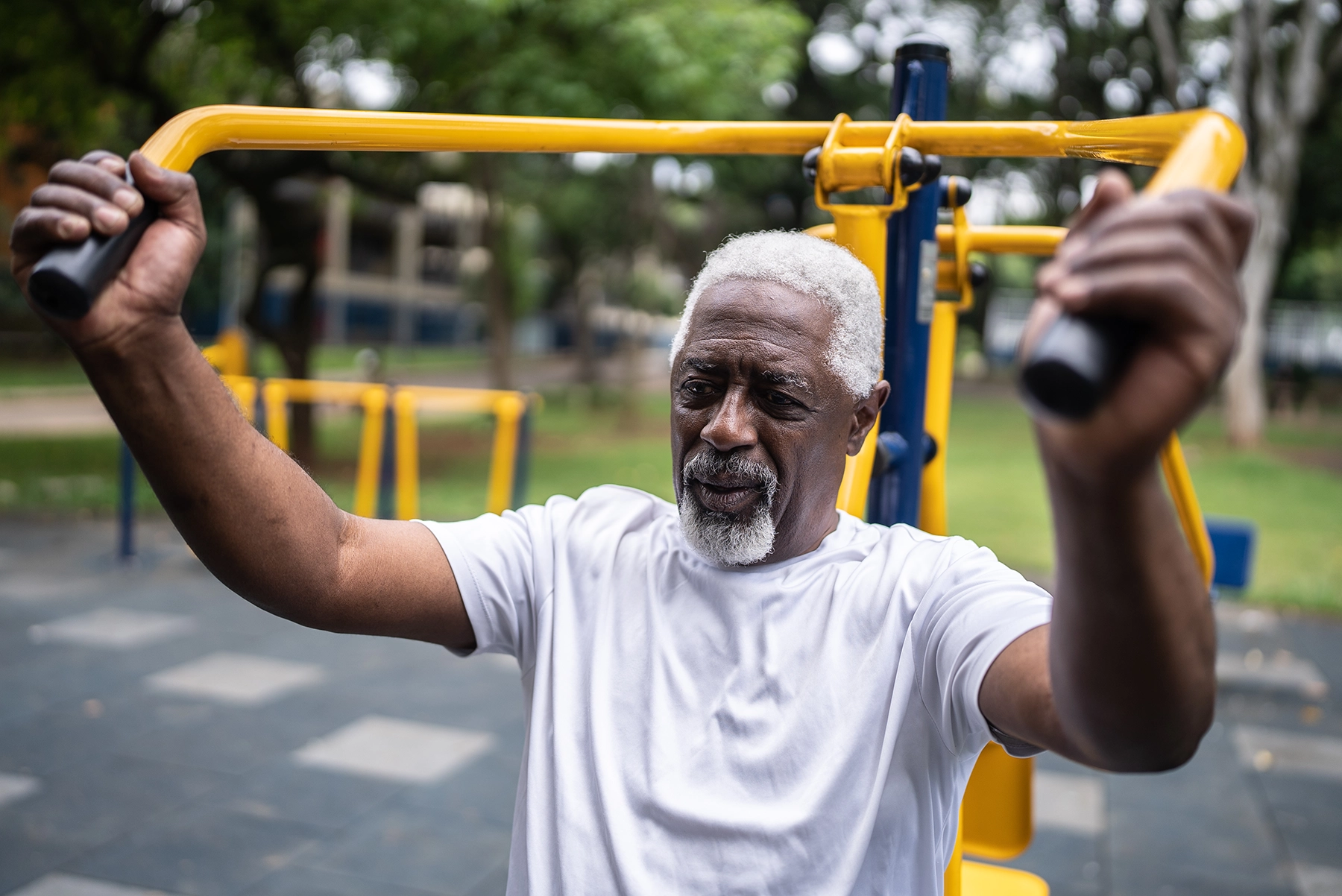 African American man uses strength training equipment in a community park.