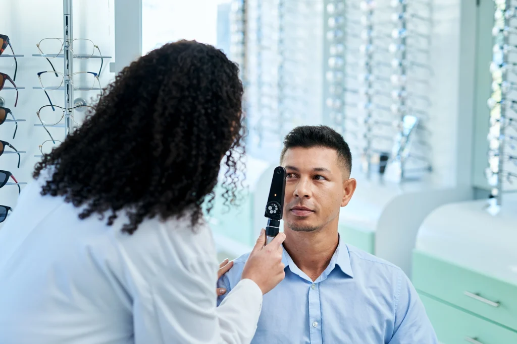 Male patient sits as optometrist evaluates his eye to see if he should get specialty contact lenses.