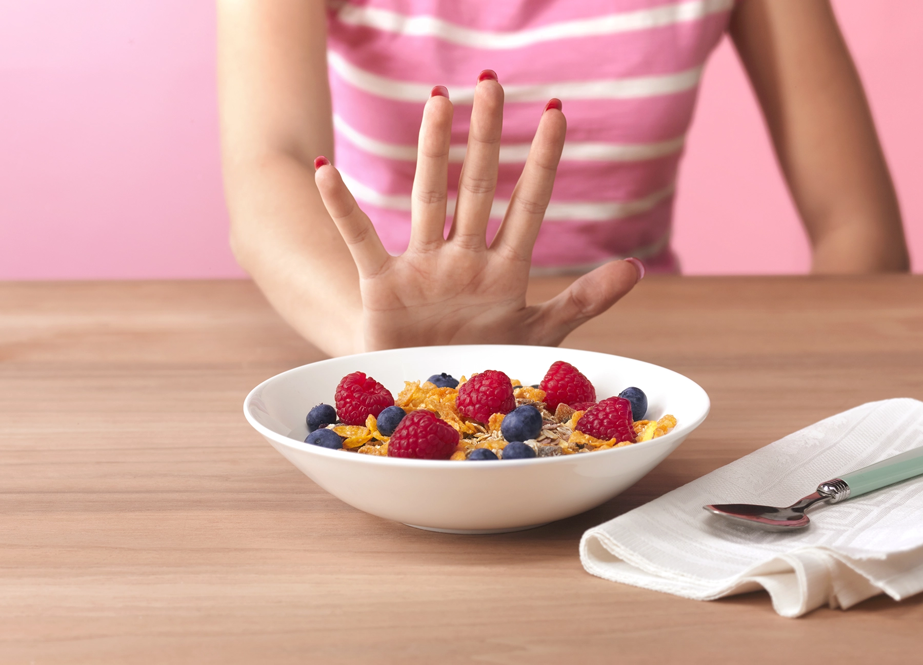 Thin teen pushes food away, signaling a eating disorder.