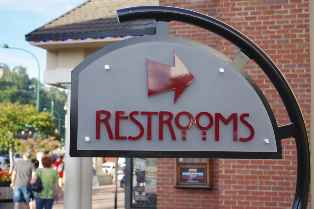 Nice photo of a restroom sign in front of a brick building.