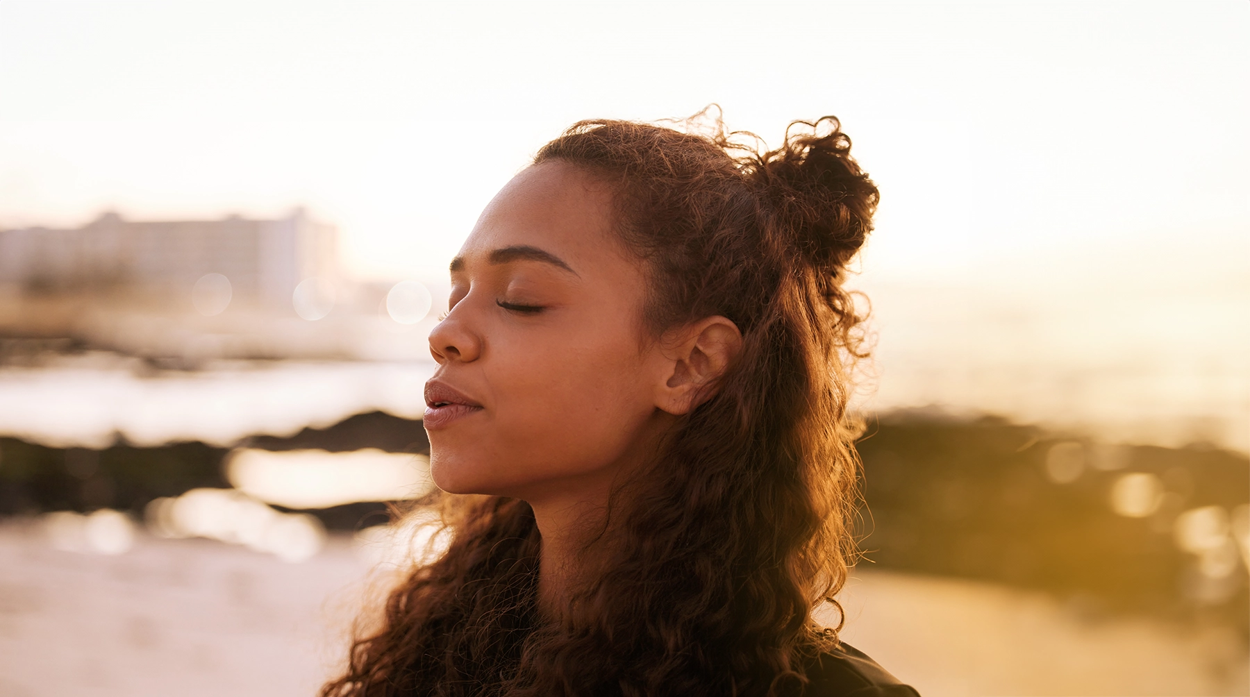 Young woman meditates on the beach, listening to the waves.