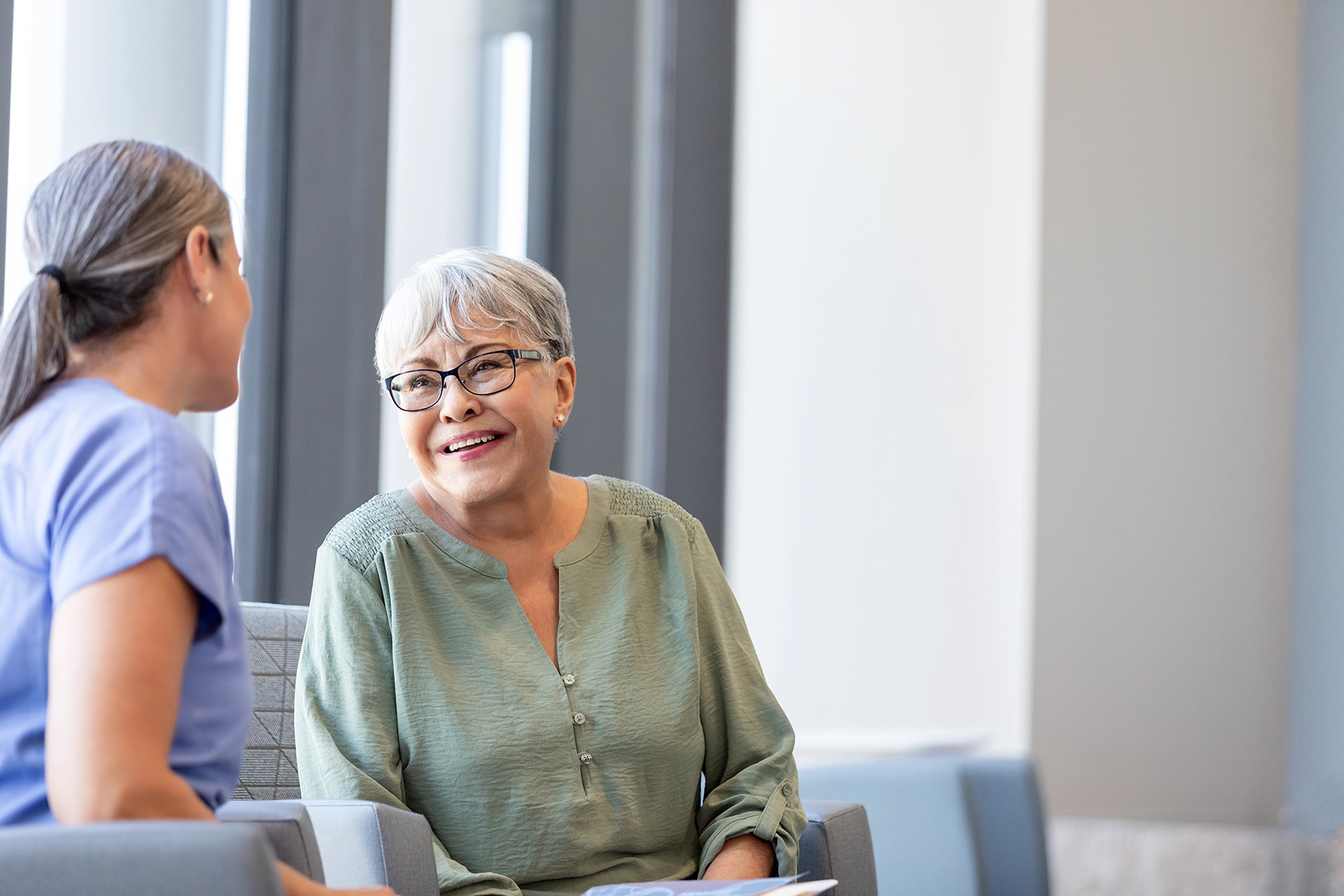 Older Hispanic woman smiles while talking to doctor.