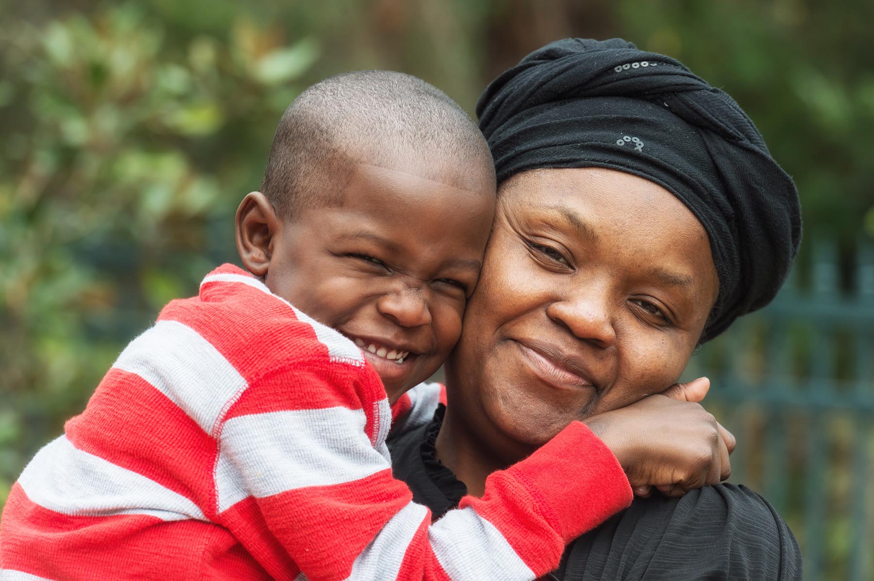 Adorable Haitian mother holds her grinning young son.