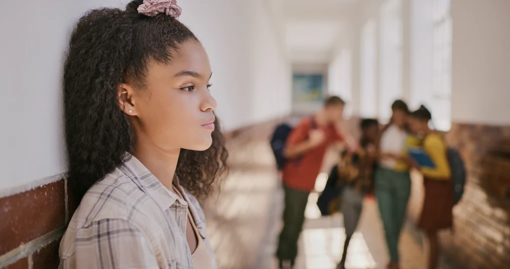 Sad, young Black girl in a hallway at school.