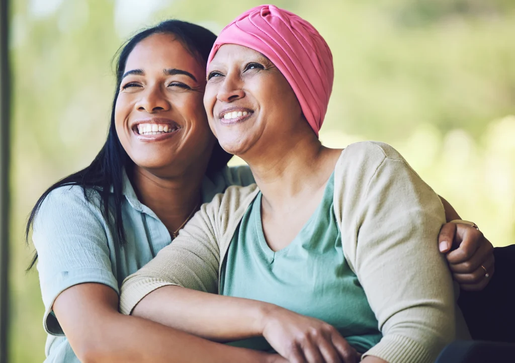 Breast cancer survvivor mom smiles broadly with her daughter after getting genetic testing.