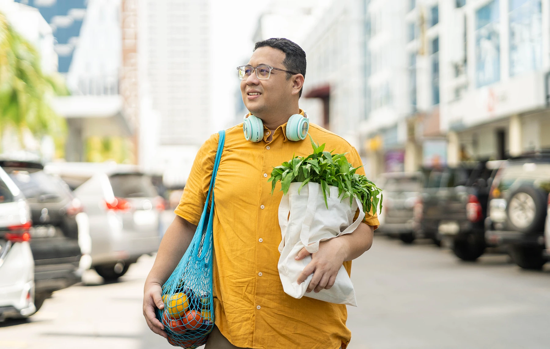 Slightly heavyset man walks down a Miami street carrying fresh veggies and fruit.