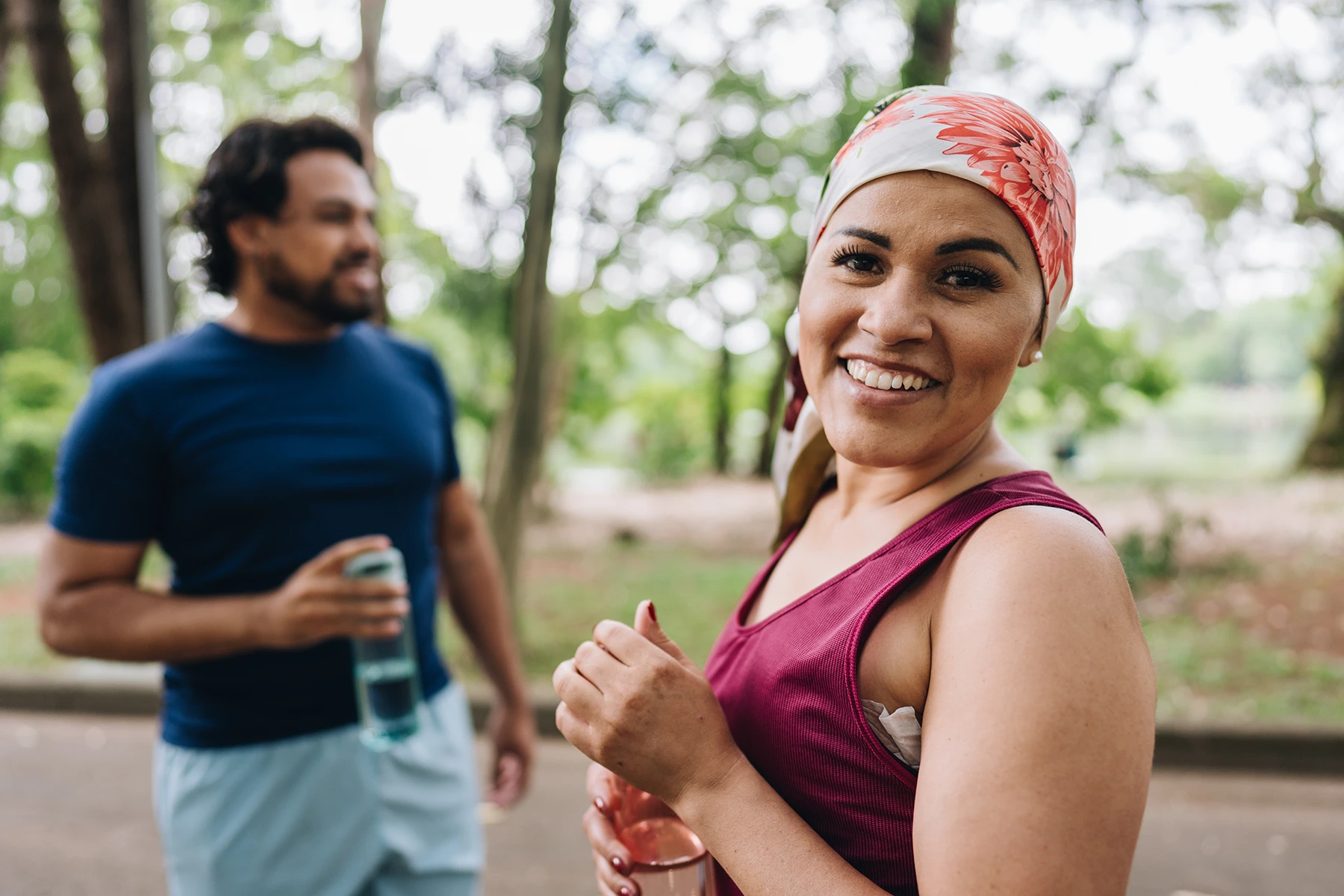 Pretty Hispanic cancer survivor exercising outside with a friend.