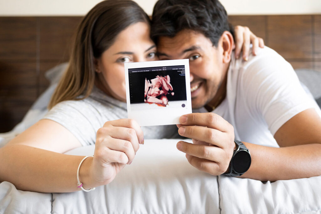 Happy couple shows their baby's ultrasound after getting male fertility treatments.