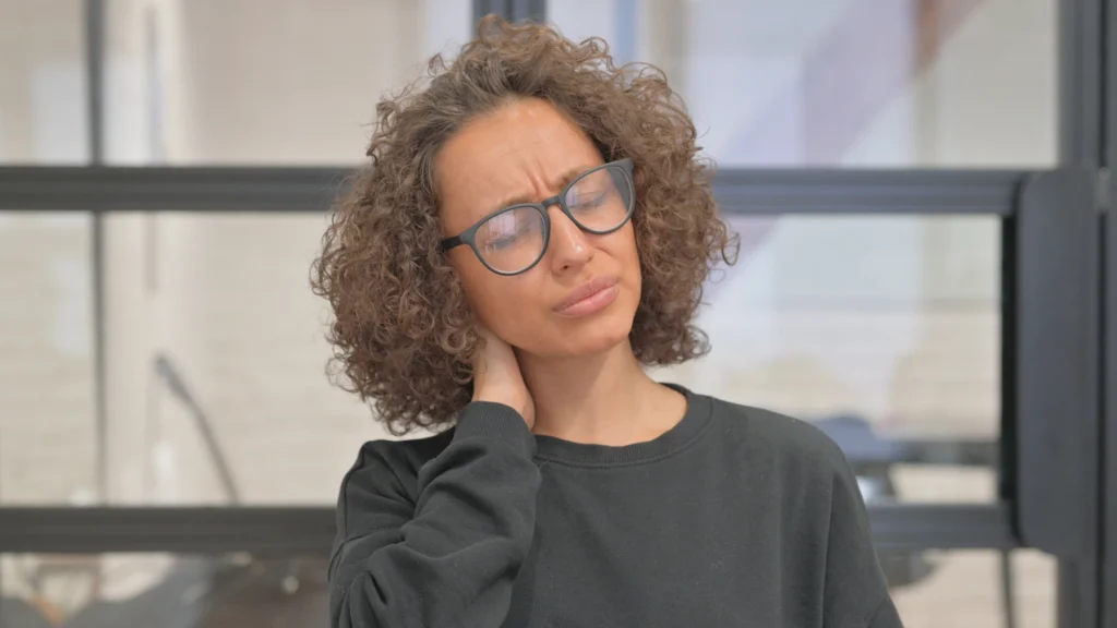 Woman holds the back of her head, wincing from the pain of her Chiari malformation headache.