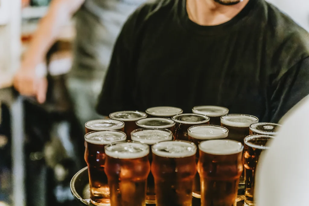 Bar server holds a serving tray filled with beers.
