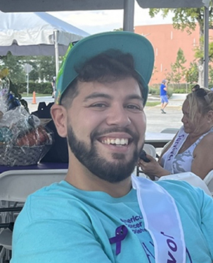 Manuel Garcia sits outside, smiling.