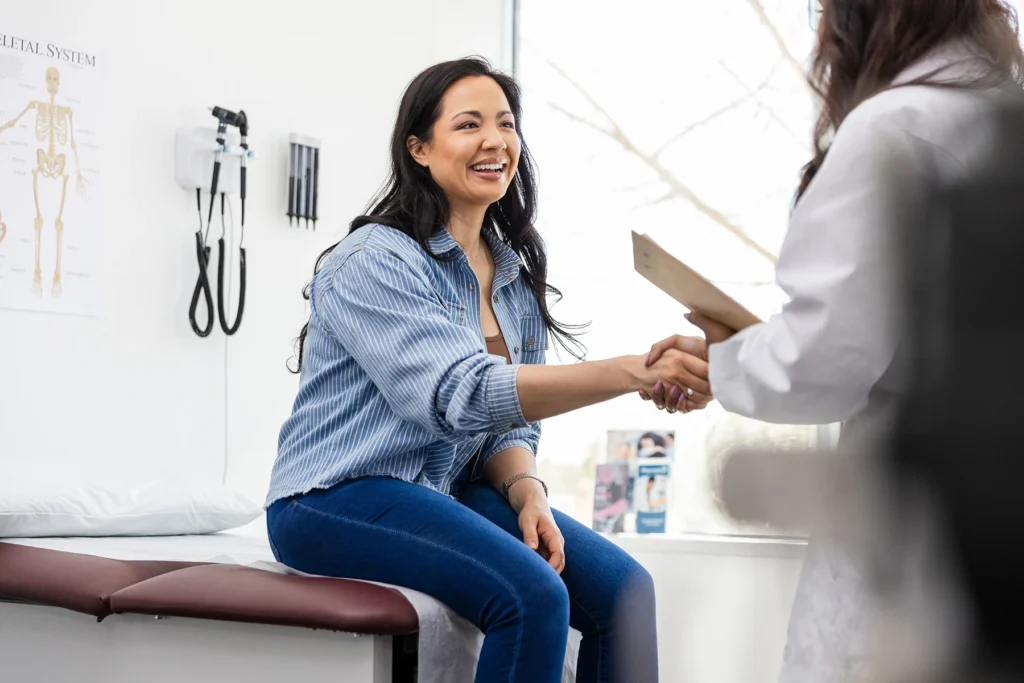 Woman shakes her doctor's hand in medical office.