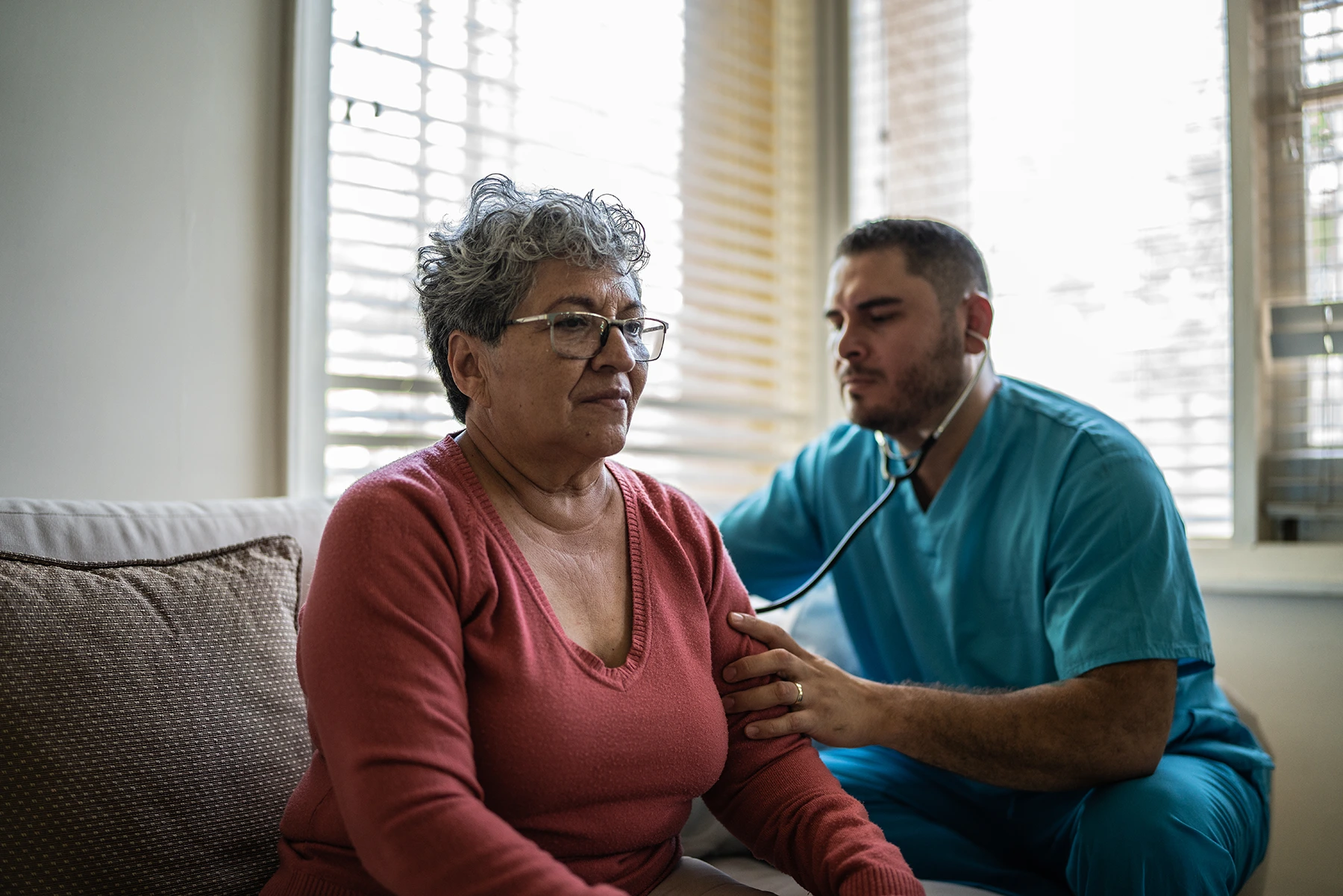 Hispanic woman leans forward so male nurse can test her lung capacity in a test for COPD. Illustrative purpose.