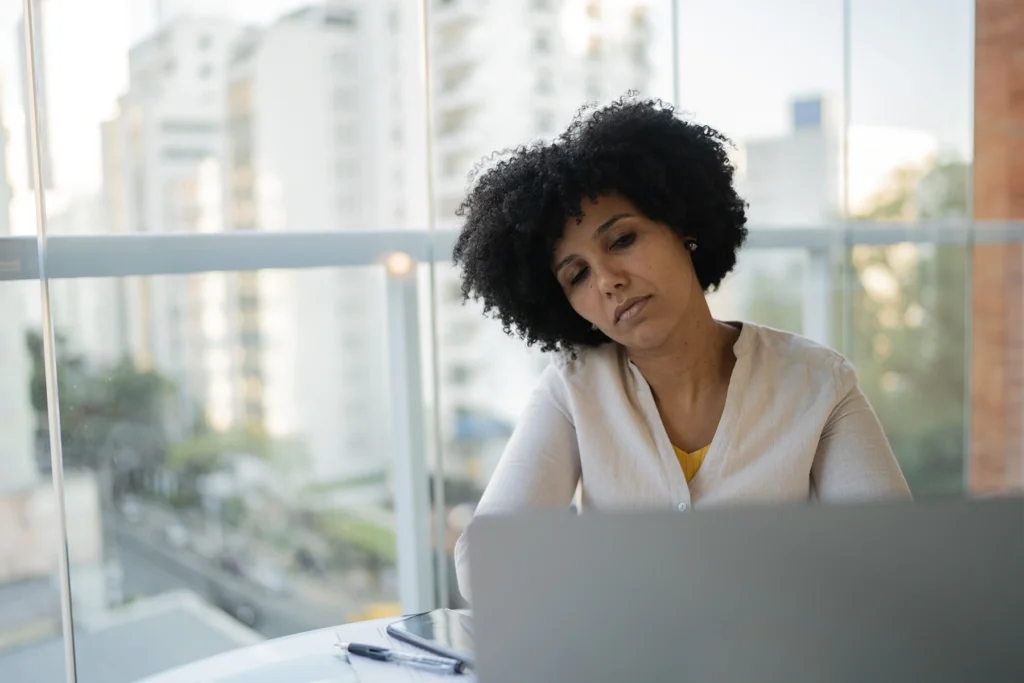 Black woman is tired while working on her laptop.