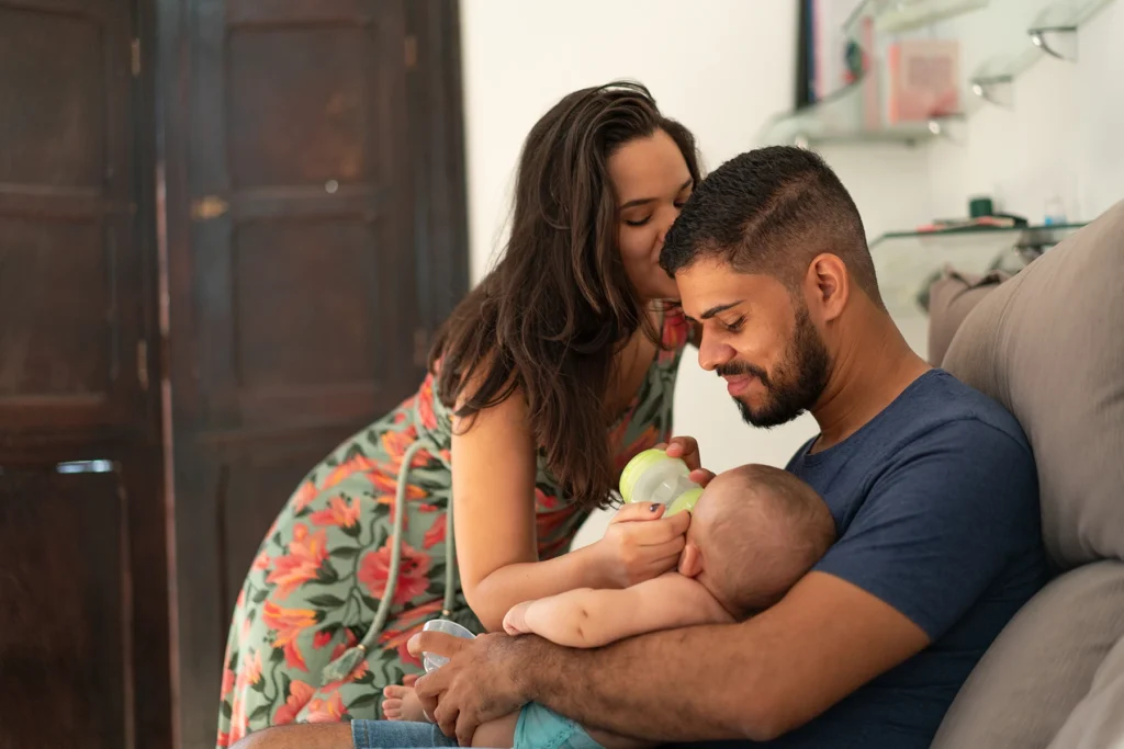 Cute couple happily feeds new baby.