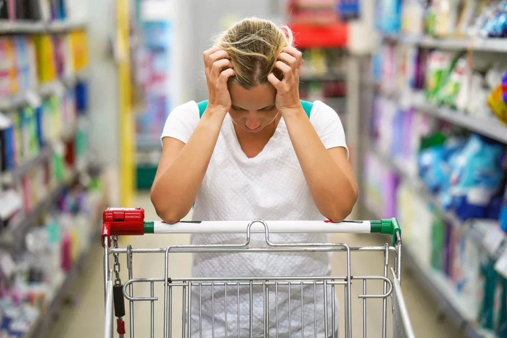 Woman clutching her hair while pushing a shopping cart.