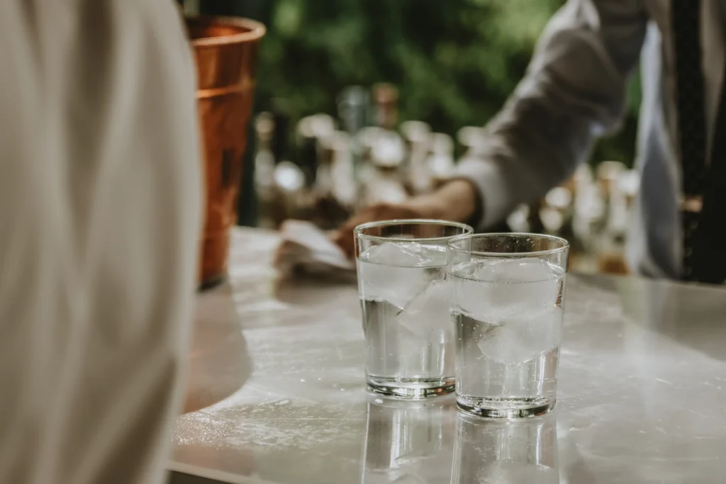 2 glasses of water sit on. a bar, ready to be served because the patron doesn't crave alcohol, thanks to Naltrexone