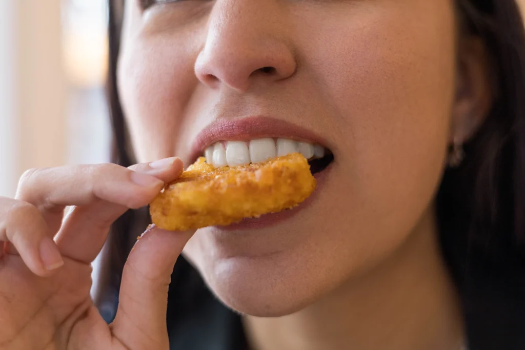 Close up of woman biting into a chicken nugget