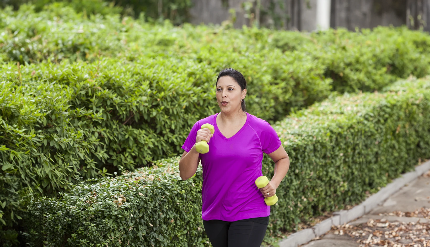 Middle aged Hispanic woman walks with weight in her hands. Healthy exercise during perimenopause