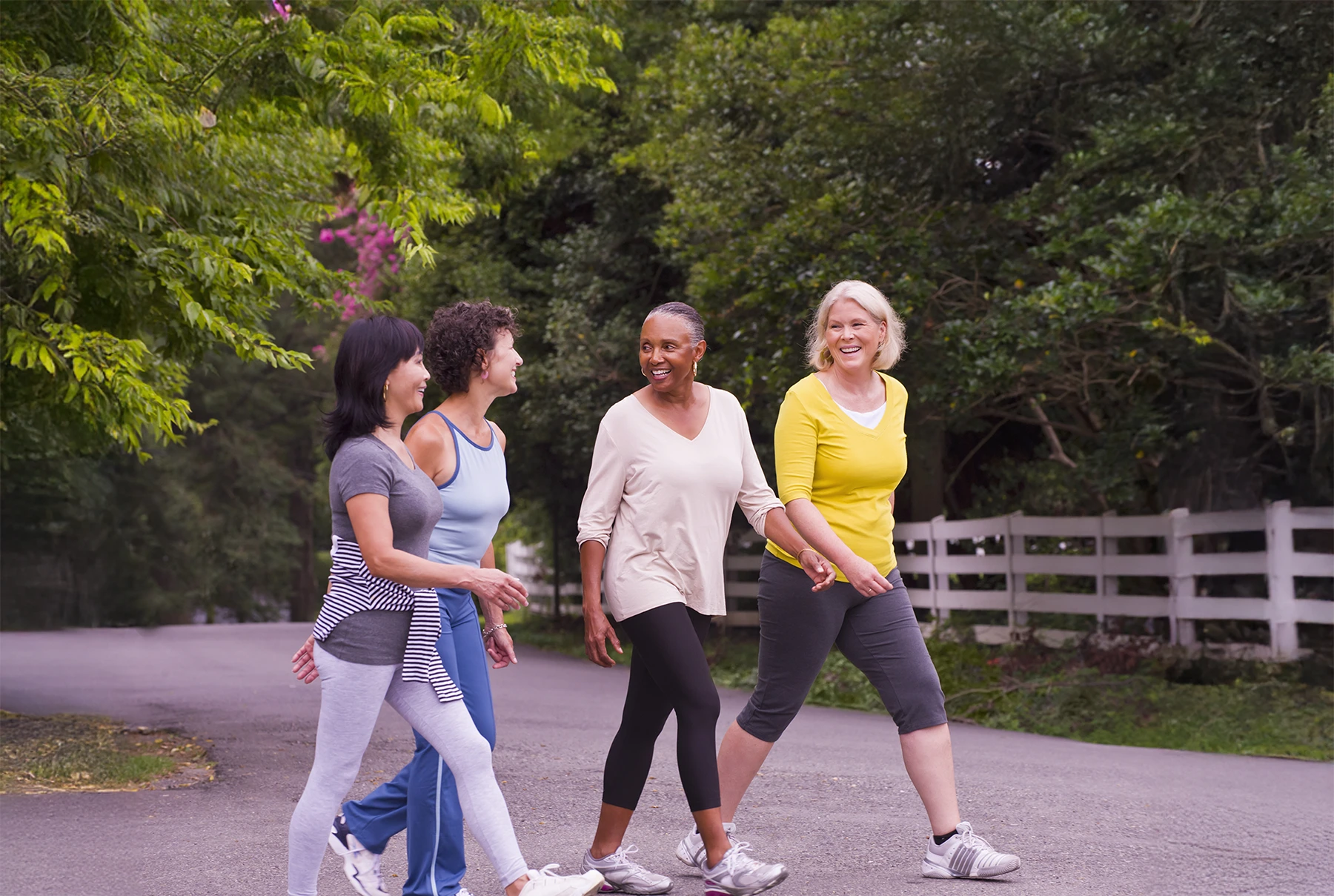 Four mature women chatting as they walk together for exercise. Example of healthy lifestyle choice to avoid health concerns like heart disease and breast cancer.