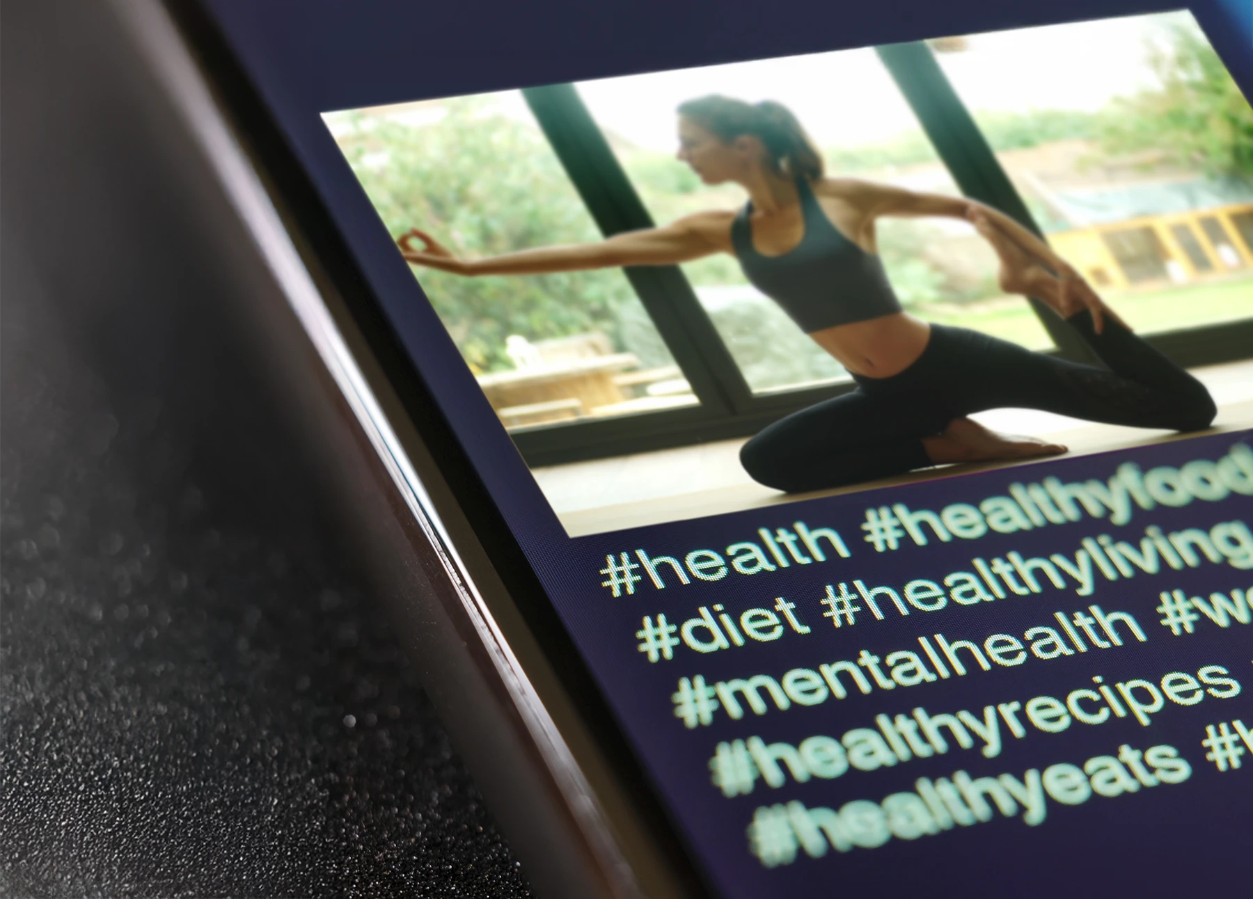 A close up of a woman doing yoga on a social media app. There are a lot of health-related hastags under the video.