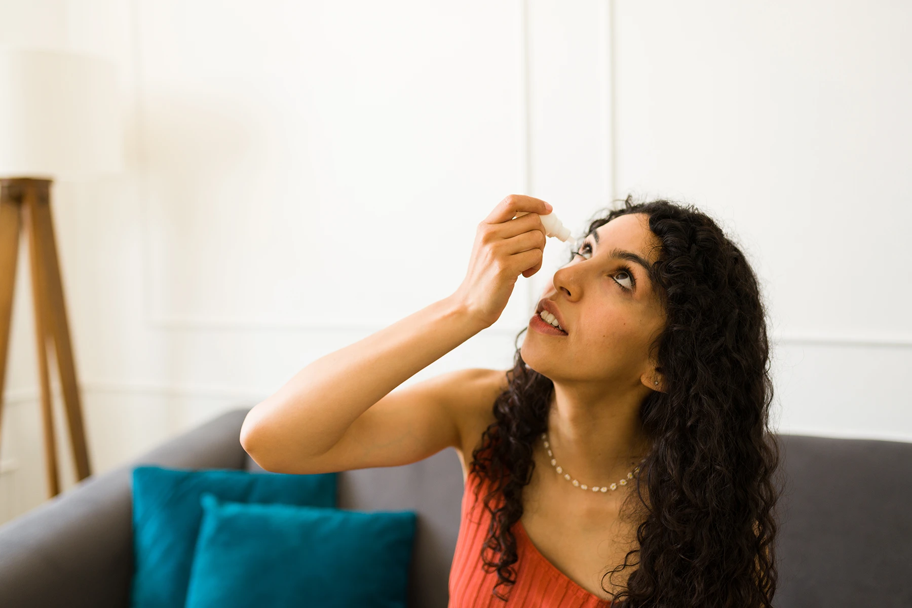Young Hispanic woman uses eye drops to fight irritation.