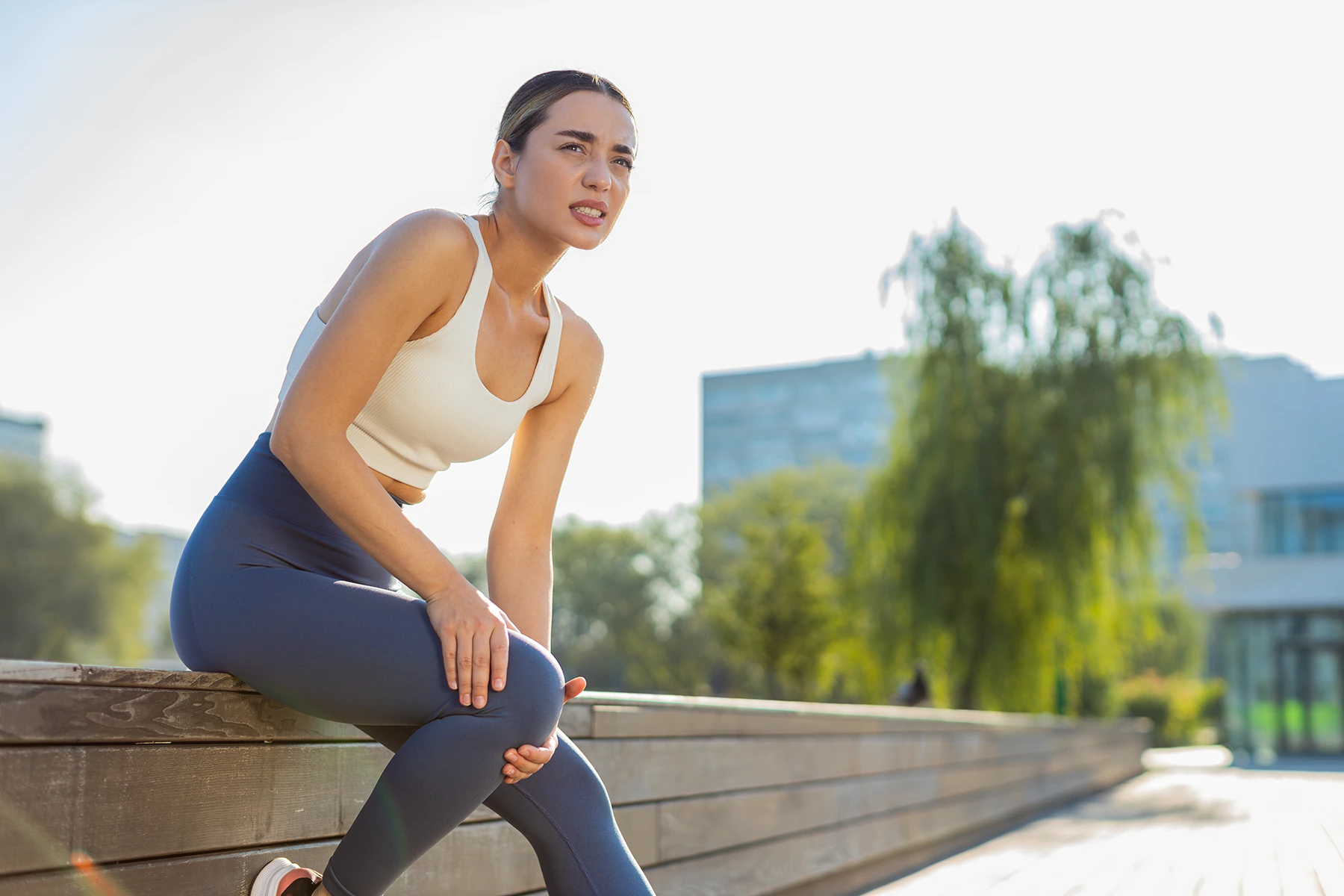 Woman rests on a run, holding her knee. Stock image.
