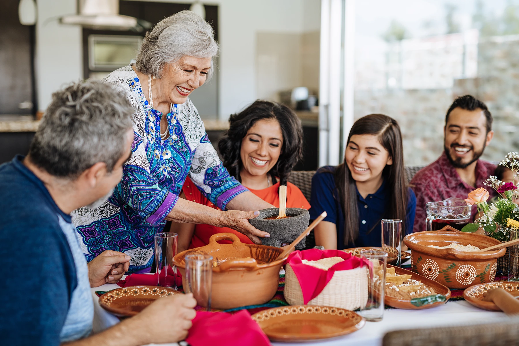 happy Hispanic family sits down for lunch together. Stock image representing healthy blood pressure at any age.