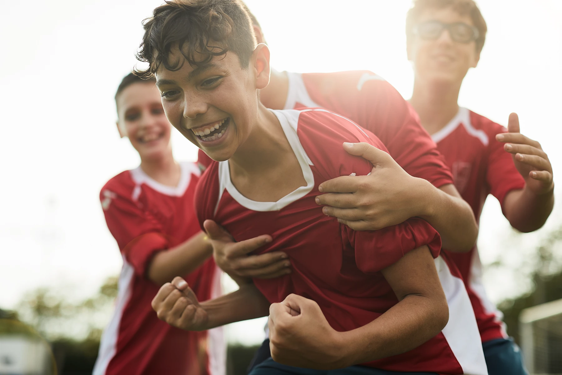 Soccer team celebrates goal by young player. Image represents active happy teens who can prevent injury.