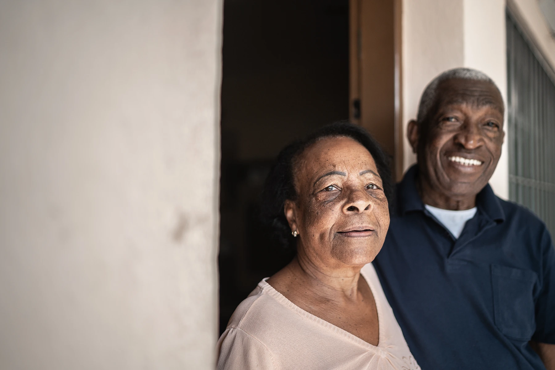 Elderly Black Hispanic couple stands in doorway. Educational story on dementia.