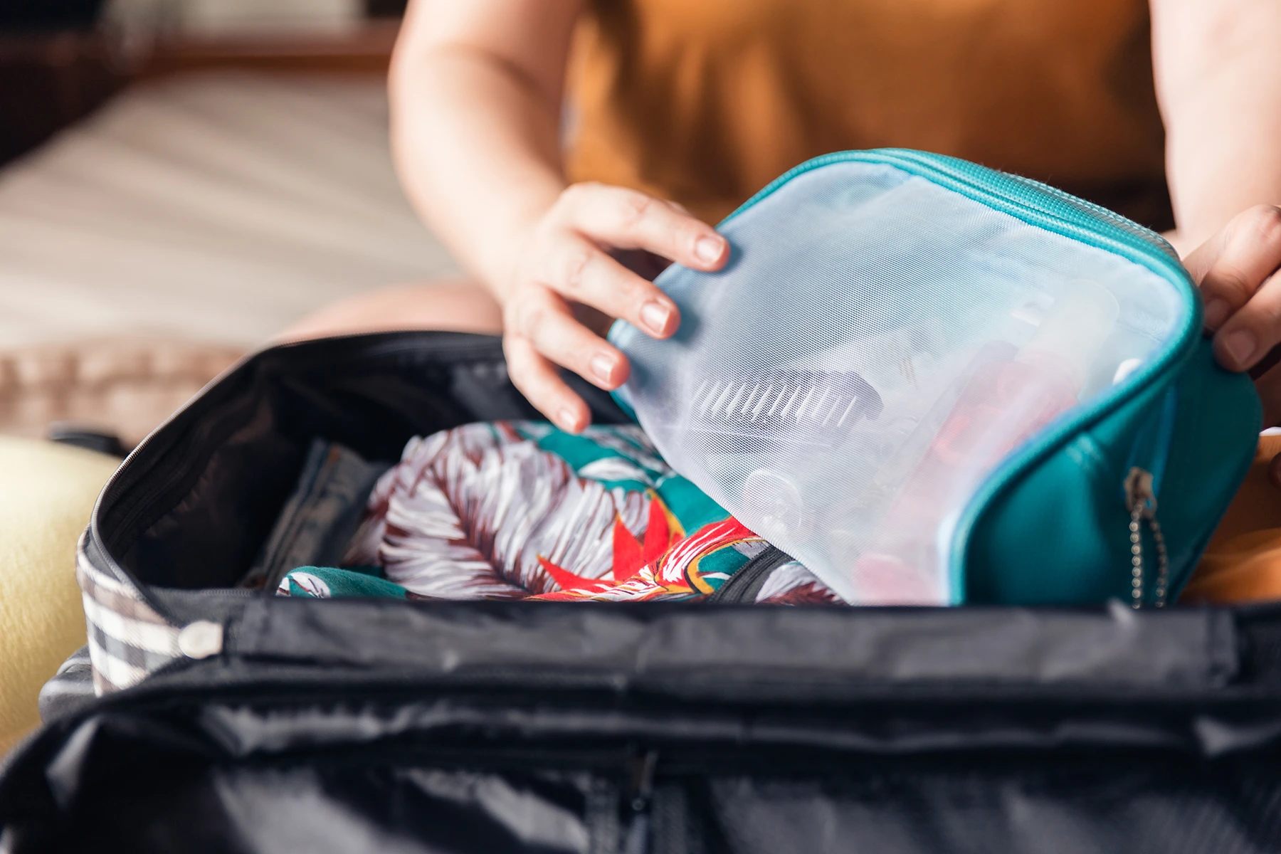 Close-up of person packing a suitcase getting ready to travel.