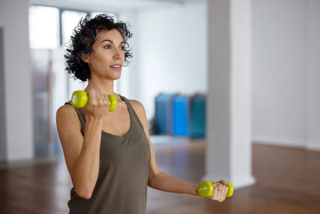 Woman lifting small weights to build bone health.