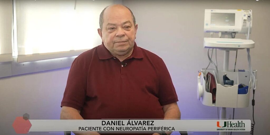 Patient Daniel Alvarez seated in a medical room at UHealth University of Miami Health System, with visible medical equipment and a monitor in the background.