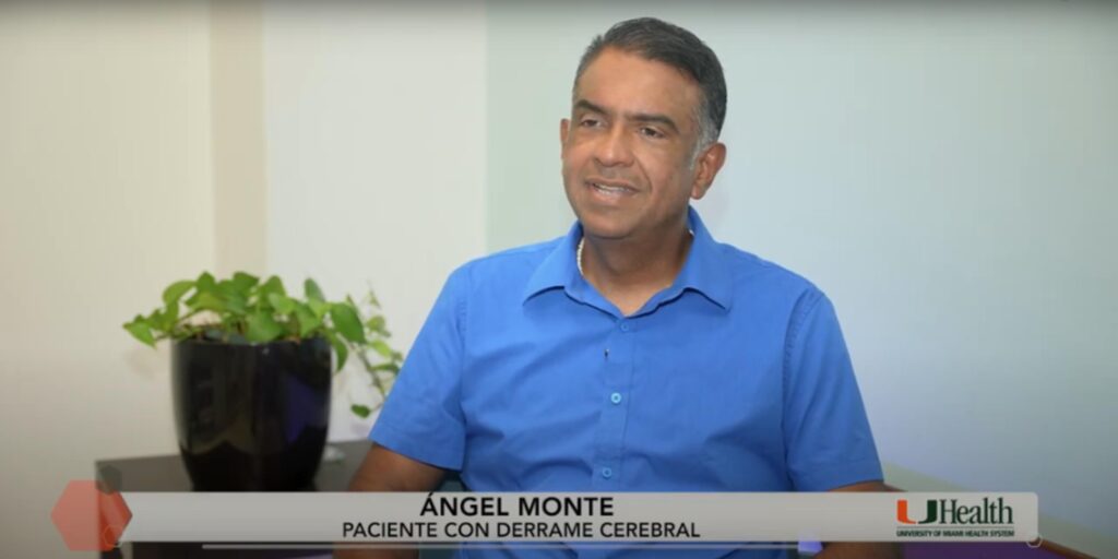 A seated individual wearing a blue shirt is partially visible, with their face obscured. A black potted plant is placed to the left. Text at the bottom reads: “ÁNGEL MONTE PACIENTE CON DERRAME CEREBRAL” and “UHealth UNIVERSITY OF MIAMI HEALTH SYSTEM