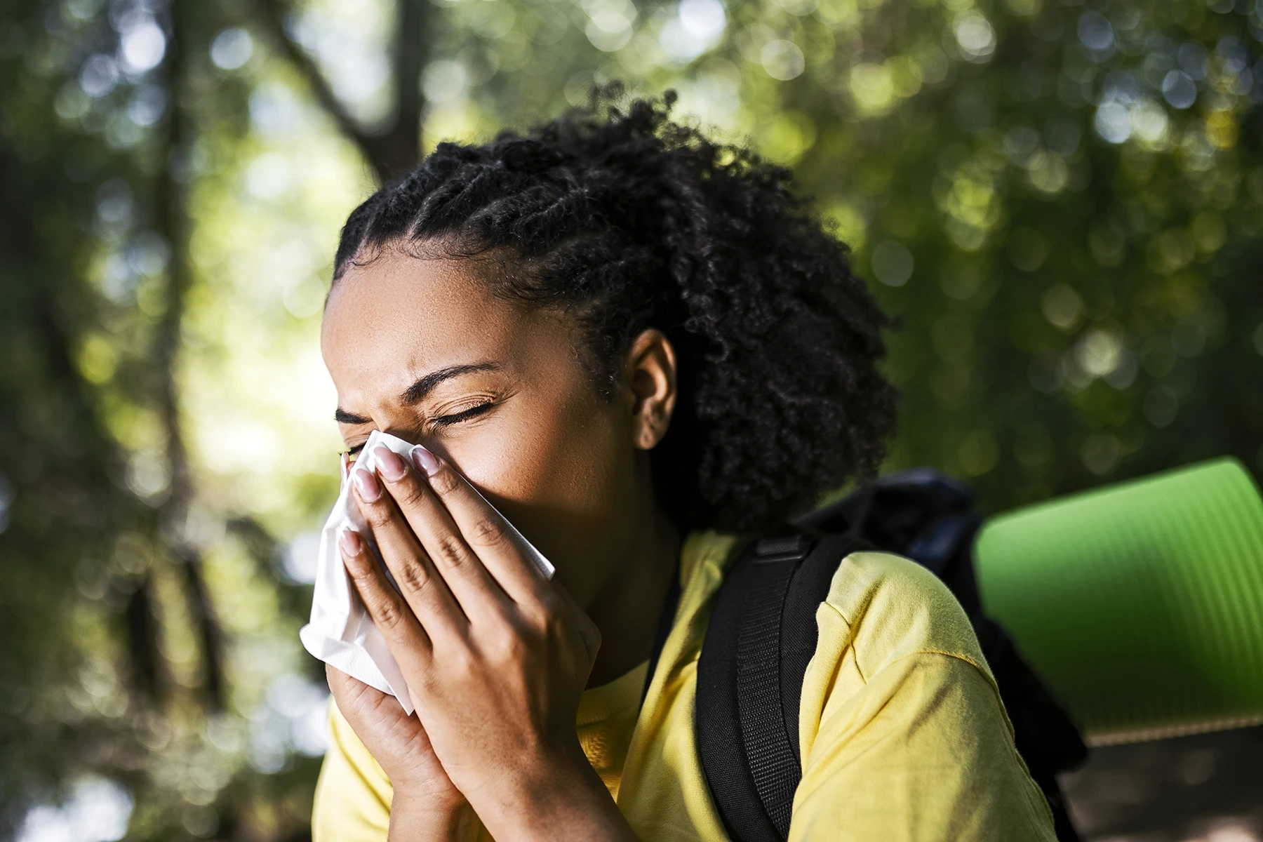 Gettyimage of pretty woman sneezing while walking outside.