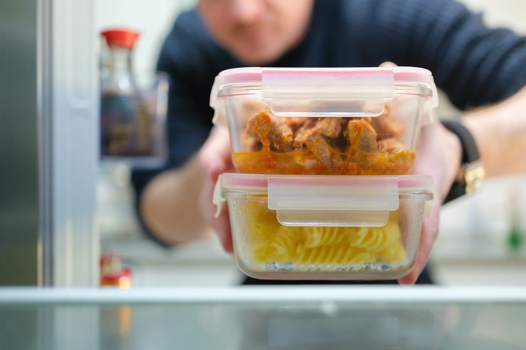 Photo of man storing food in a refrigerator.