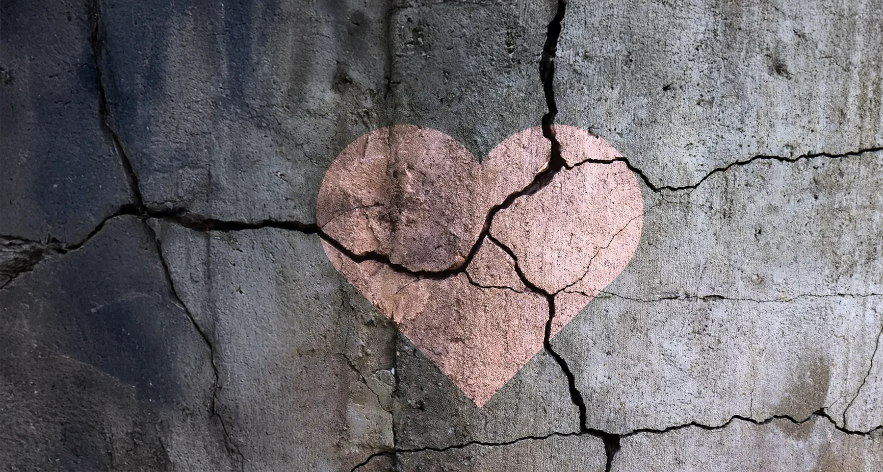 Broken pavement with a painted pink heart. Reflecting grief.