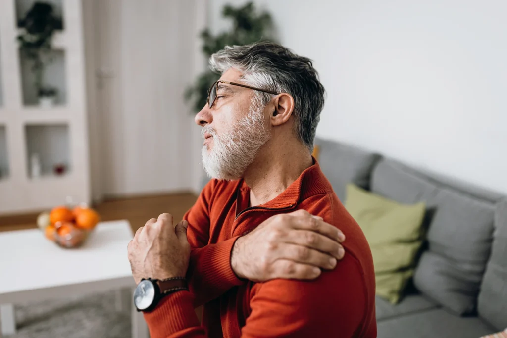 Older man holds his painful shoulder. due to joint pain.