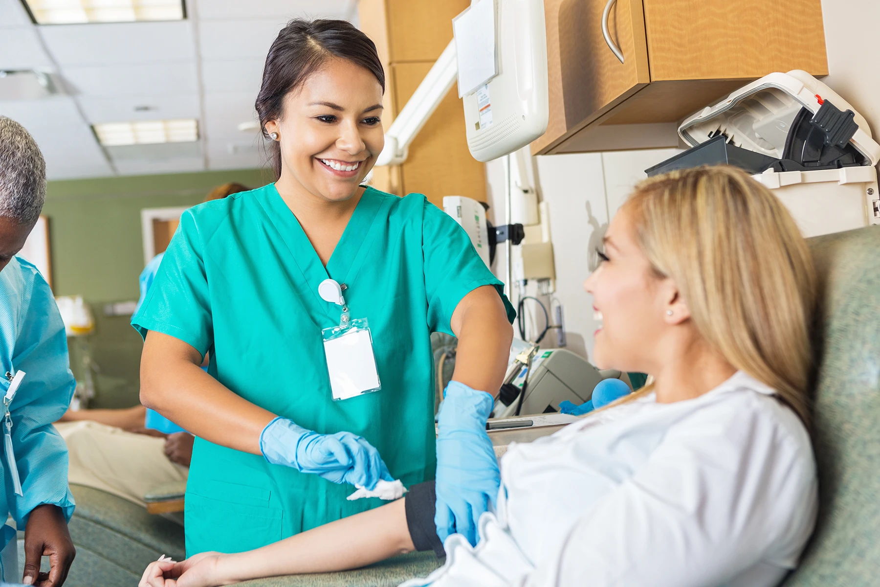 Nurse swabs away blood on a happy woman's arm after a blood test.